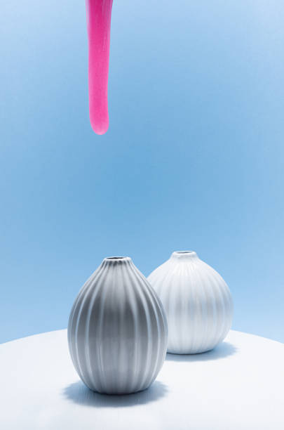 istock Pink viscous slime with glowing glitter flow down as stream and strives to get on white vase on white wood table, blue wall. Contemporary art concept of fashion. 1337211899