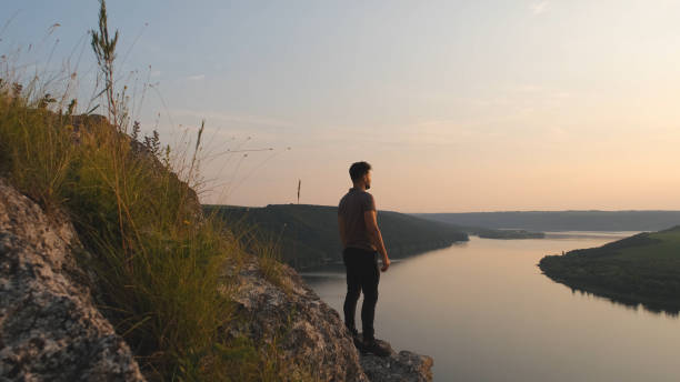 istock The young man stands on rocky mountain on beautiful river background 1337212058