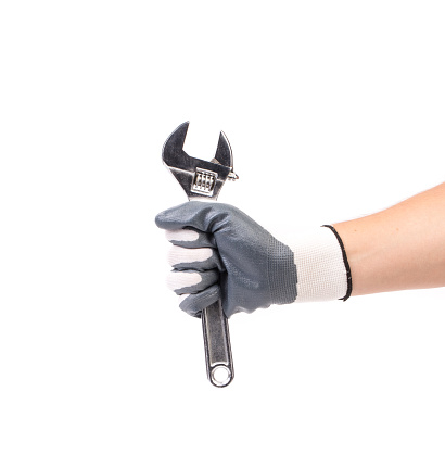 A gloved hand holds an adjustable wrench. Isolated over white background. Close-up.