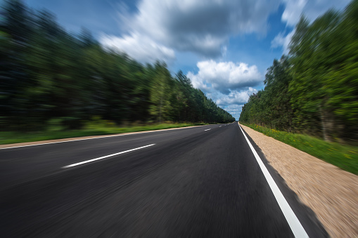 Speed concept image. Motion blurred asphalt road under blue sky
