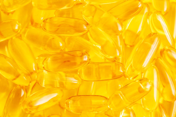 olio di pesce omega 3 sfondo giallo astratto - vitamin e cod liver oil vitamin pill capsule foto e immagini stock