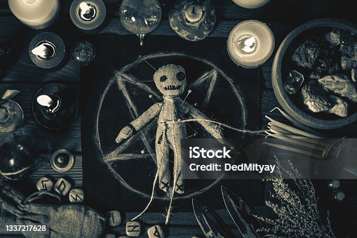 istock Voodoo Magic concept. Voodoo doll studded with needles with pierced rag heart on pentagram and around burning candles. Spooky or eerie magical esoteric ritual, black and white photo 1337217628
