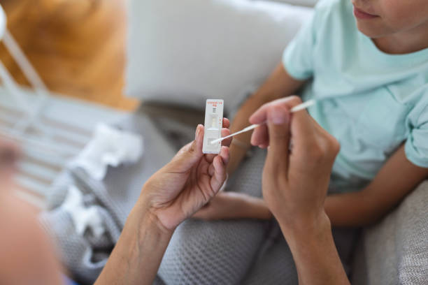 Mother is taking rapid covid-19 test at home to her sick daughter at home. Mother performing nasal swab on her child taking example to analyze if patient is positive for the infectious diseas