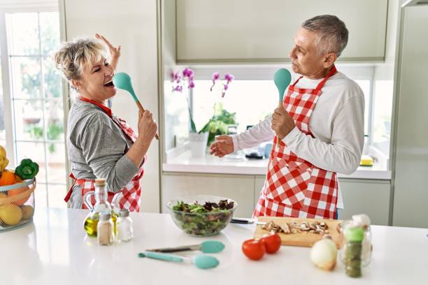 istock Senior caucasian couple smiling happy cooking at the kitchen. Singing using spoon as a microphone. 1337222043