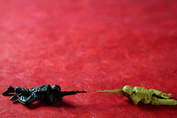 Two plastic toy soldier over red pointing with fire gun, war metaphor
