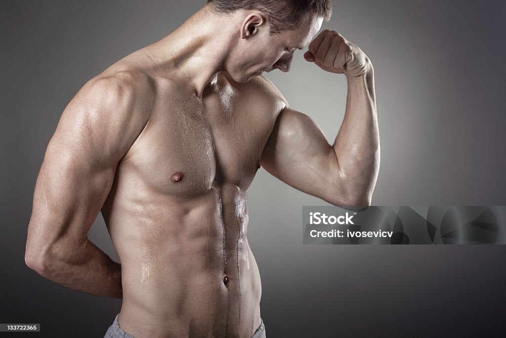 Male Figure Flexing Biceps Muscular male figure in high contrast lighting setup - model is flexing his left arm bicep muscle Abdomen Stock Photo