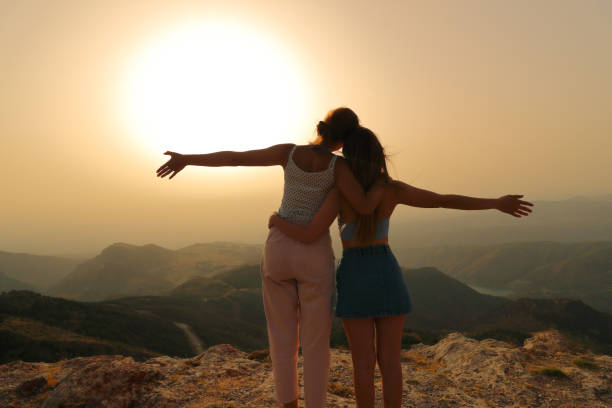 Friends celebrating outstretching arms at sunset