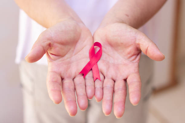 istock Focus on mature hand holding a pink ribbon isolated on white. 1337225643