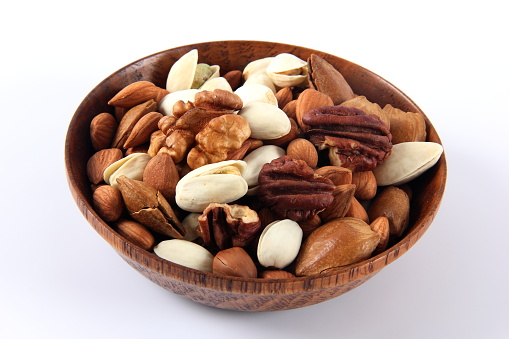 Wooden bowl with mixed nuts on white background