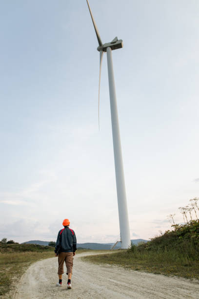 istock Man walking in front of wind turbines 1337226130