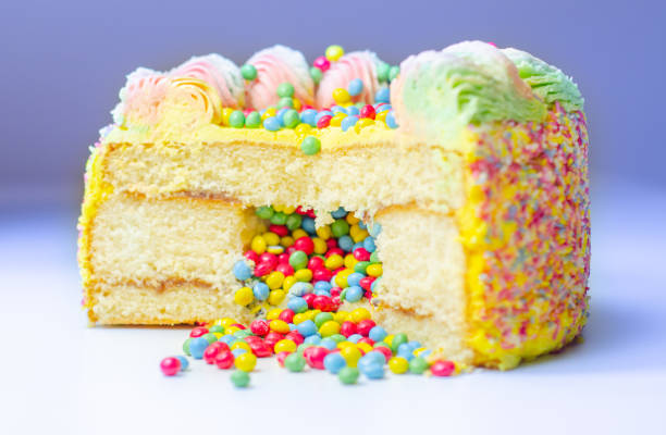 istock Madeira sponge coated with yellow colour frosting, layered with plum and raspberry jam, filled and topped with multicolour chocolate nibs and decorated with multicolour frostings and sugar decorations 1337226949