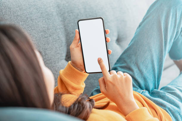 istock Woman using mobile smartphone with blank white screen on a sofa in living room. 1337229844