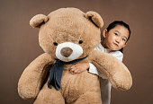Little Girl Embracing Teddy Bear on Brown Background