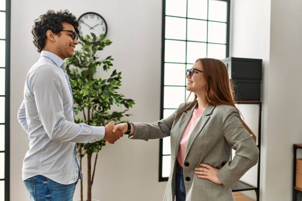 istock Two business workers smiling happy shaking hands at the office. 1337230020