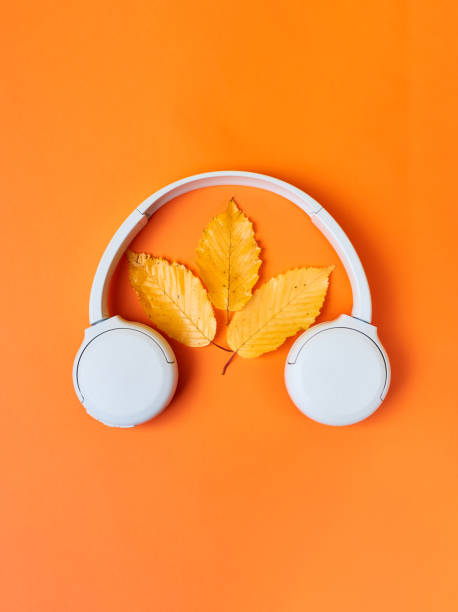 istock Fall flat lay composition with realistic leaves and white headphones on orange background. Autumn podcast background. Autumn playlist concept. Vertical photo 1337230203