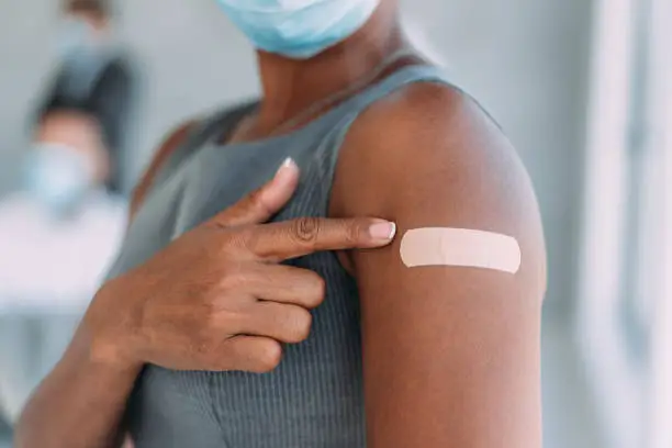 Photo of Businesswoman showing her arm after getting vaccinated in the office.