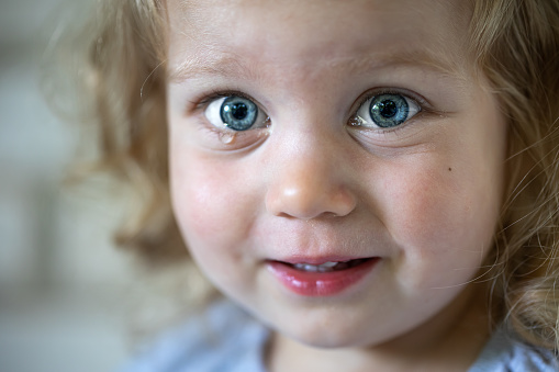 Portrait of a little girl with big blue eyes, tear-stained eyes of a child.