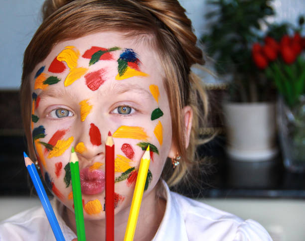 istock A girl stained with paint holds colored pencils. 1337234175