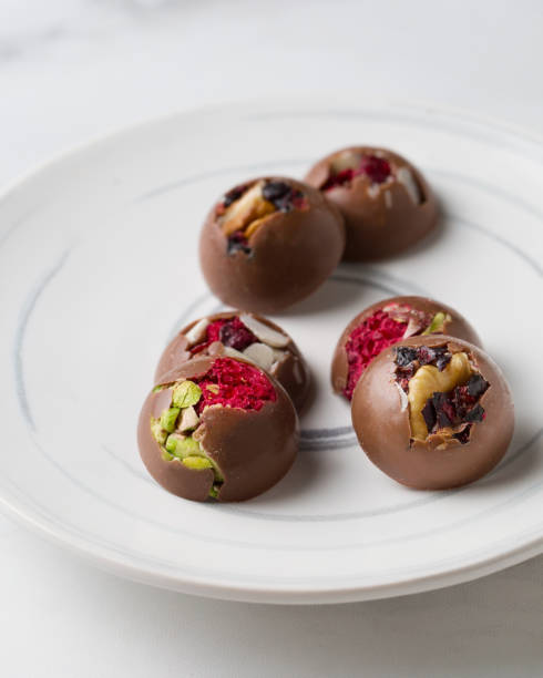 istock Chocolate candies with nuts. Delicious dessert on a light background. Sweets on a white plate. Macro photography of sweets. 1337236688