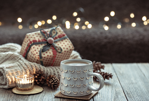 Cozy Christmas composition with a cup and festive decor details on a blurred dark background with bokeh.
