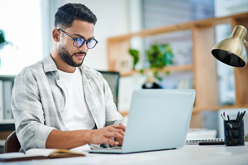 Happy business professional wearing sweater analyzing documents while sitting at desk in office