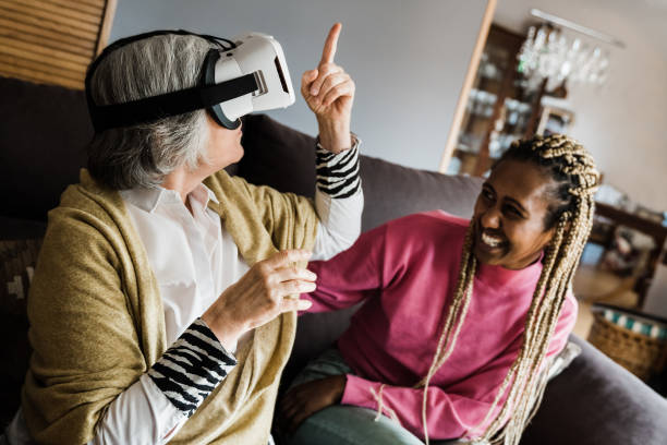 Multi generational people using virtual reality headset indoors at home - Technology trend and joyful senior lifestyle concept - Focus on vr googles