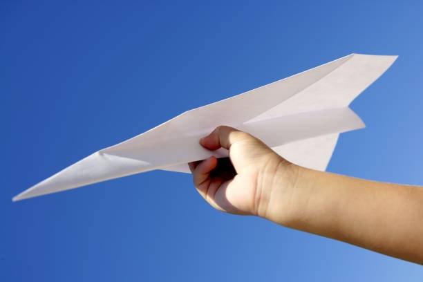 istock Paper airplane in children hand over blue sky 1337241347