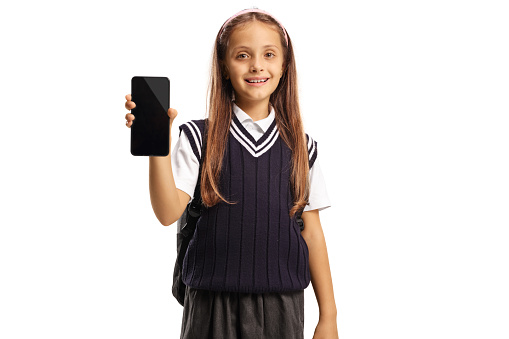 Cute schoolgirl showing a smartphone isolated on white background