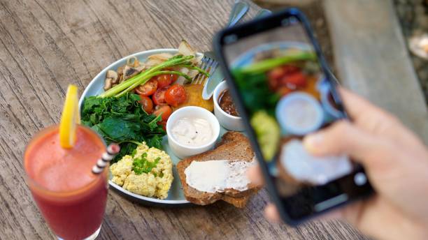 Top view of human hands taking pictures of a healthy plant based brunch with a smartphone Top view of human hands taking pictures of a healthy plant based brunch with a smartphone image based social media photos stock pictures, royalty-free photos & images