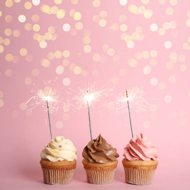 istock Birthday cupcakes with sparklers on pink background 1337243664