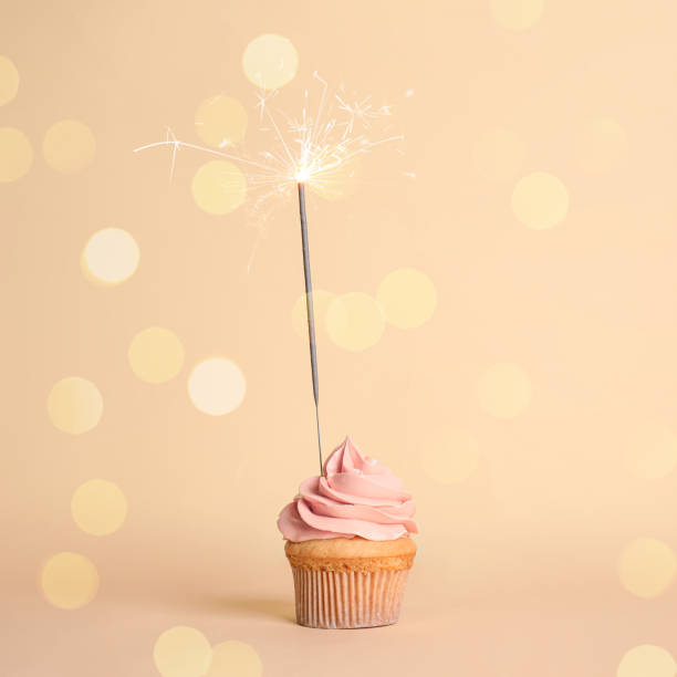 istock Birthday cupcake with sparkler on beige background 1337243672