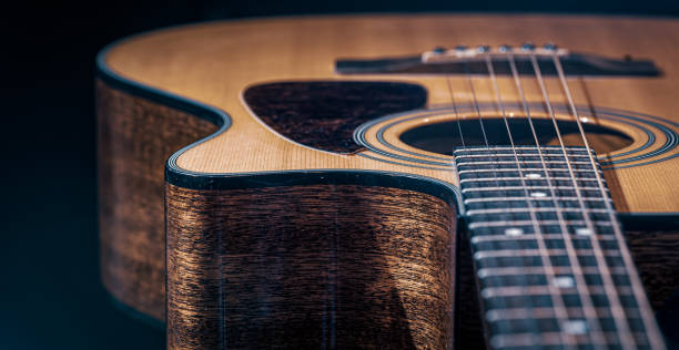 Close-up of a classical acoustic guitar with wooden texture. Part of an acoustic guitar, guitar fretboard with strings on a black background. acoustic music photos stock pictures, royalty-free photos & images