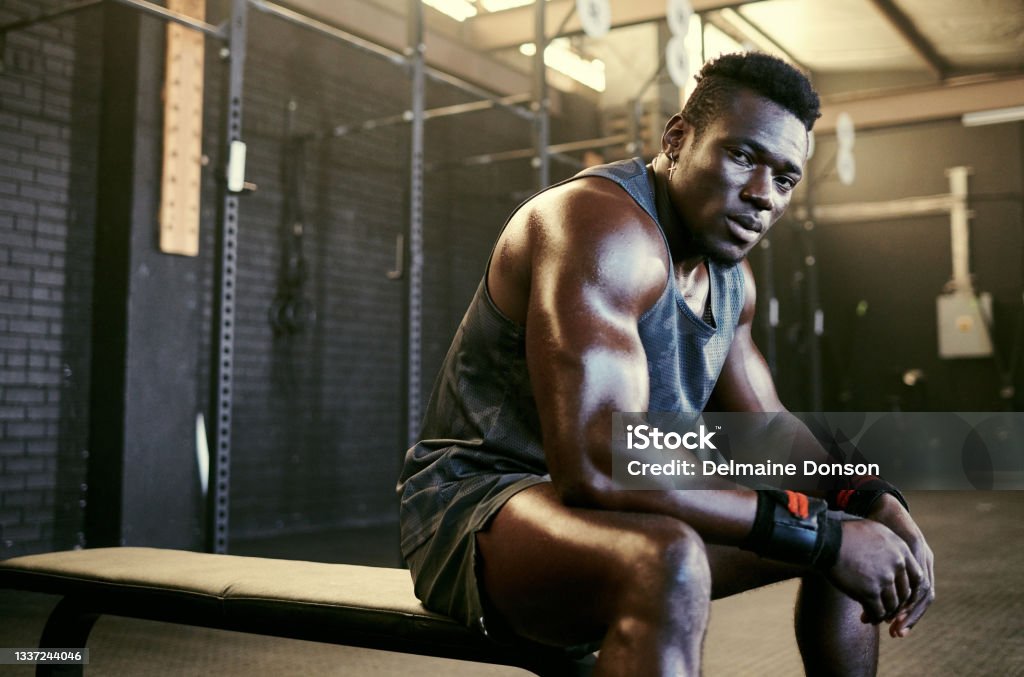 Portrait of a young fit sweaty man sitting in the gym after his workout Self motivated Body Building Stock Photo