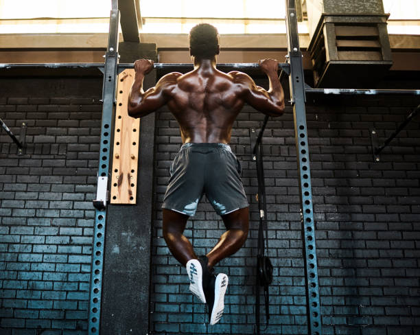 istock Rearview shot of a young man lifting doing pull ups at a gym 1337244083