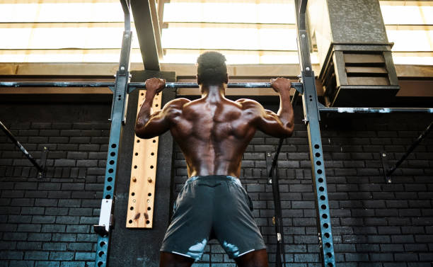 istock Rearview shot of a young man lifting doing pull ups at a gym 1337244094
