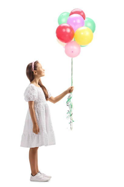 full length profile shot of a girl in a white dress balloons and looking up - junior high fotos imagens e fotografias de stock