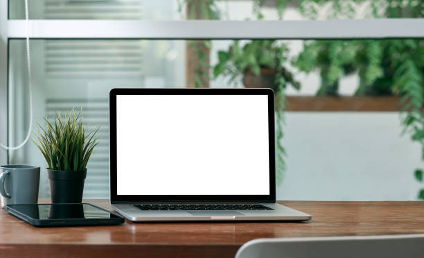 istock Mockup blank screen laptop computer on wooden table with green plant background. 1337244659