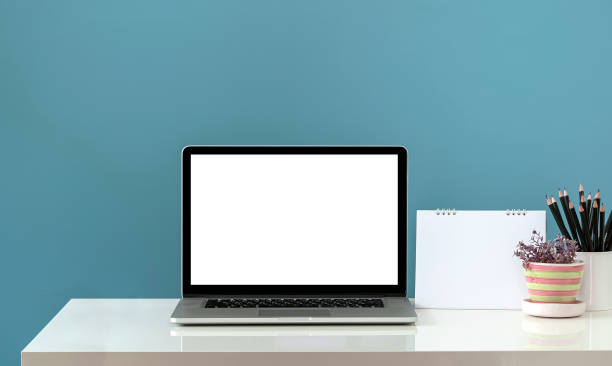 istock Mockup blank screen laptop computer and supplies on white table and light blue wall background. 1337245421