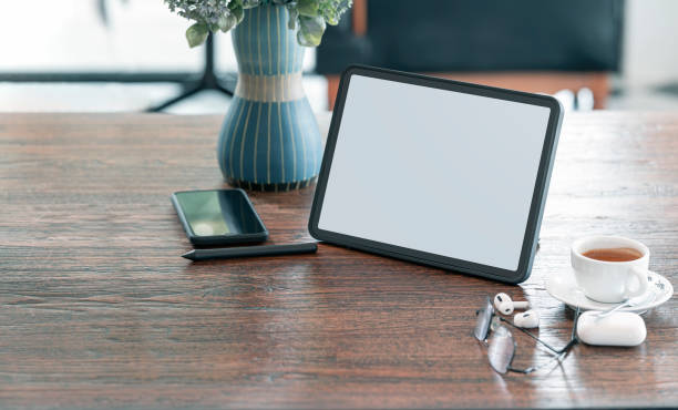 istock Blank screen tablet, gadget and coffee cup on wooden table in cafe room with copy space. 1337245448