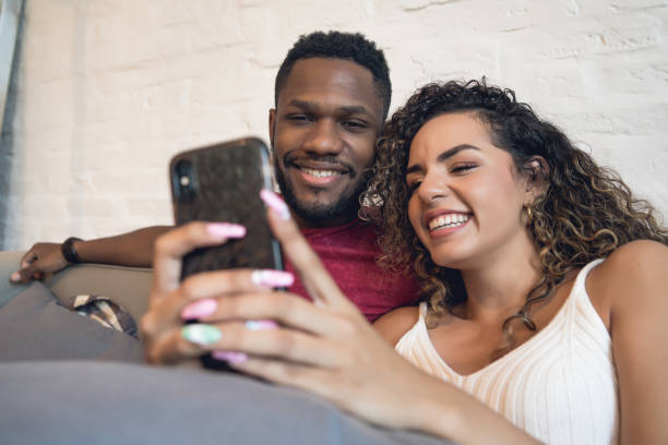 istock Couple using a mobile phone while sitting on a couch at home. 1337245661