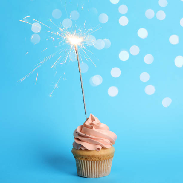 istock Birthday cupcake with sparkler on light blue background 1337245714