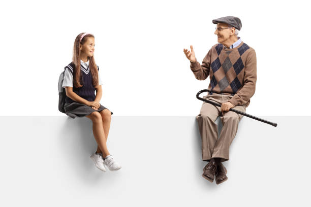 Grandfather and granddaughter sitting on a blank panel and talking isolated on white background