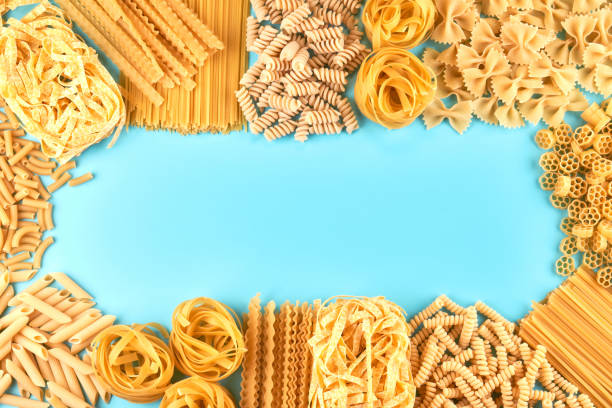 istock Frame from Assorted varieties of pasta wallpaper. Mix macaroni, spaghetti on blue background with copy space 1337246278