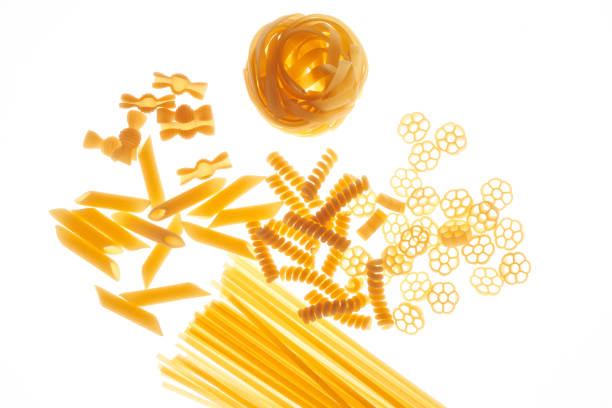 Mix of different varieties of pasta on white background, bottom lighting, assorted macaroni\