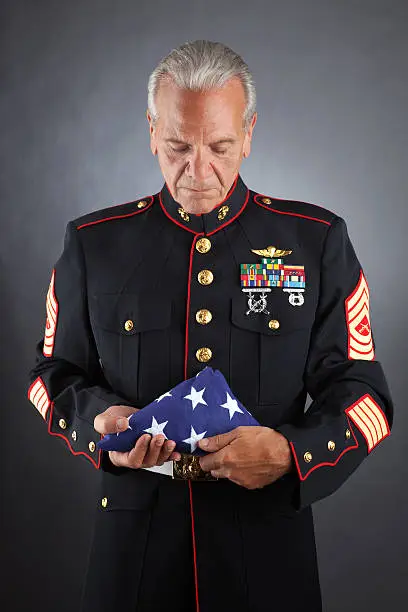 A military member holds a folded flag