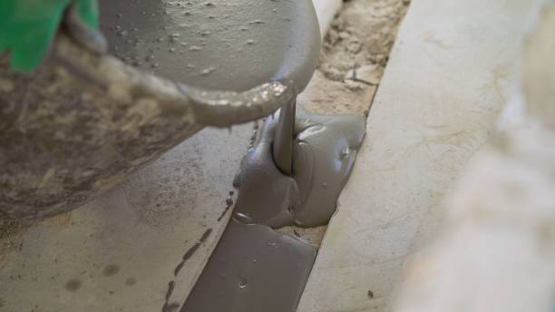 istock The solution is poured into the gap in the floor. dark bucket. Floor leveling solution. A bucket from which the mortar is poured. Seal the hole in the floor with mortar 1337250590