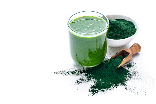 High angle view of a drinking glass filled with Spirulina smoothie and a bowl with Spirulina powder isolated on white background. High resolution 42Mp studio digital capture taken with Sony A7rII and Sony FE 90mm f2.8 macro G OSS lens