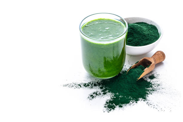 Spirulina smoothie isolated on white background High angle view of a drinking glass filled with Spirulina smoothie and a bowl with Spirulina powder isolated on white background. High resolution 42Mp studio digital capture taken with Sony A7rII and Sony FE 90mm f2.8 macro G OSS lens chlorella stock pictures, royalty-free photos & images