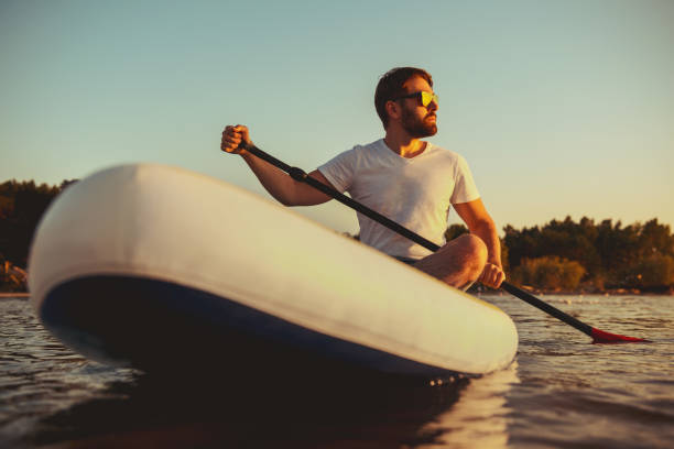 istock Man hipster sits on paddle board at sunset 1337253343