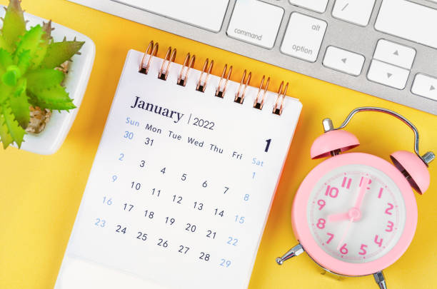January 2022 desk calendar and pink alarm clock January 2022 desk calendar and pink alarm clock with keyboard computer. january stock pictures, royalty-free photos & images